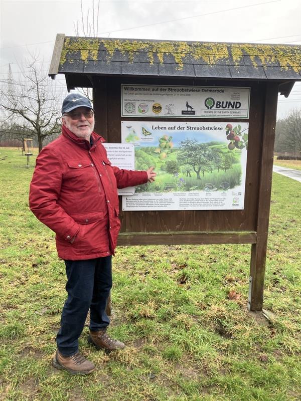Bild von Herr Bronold, der auf ein Schild zeigt mit dem Titel "Leben auf der Streuobstwiese